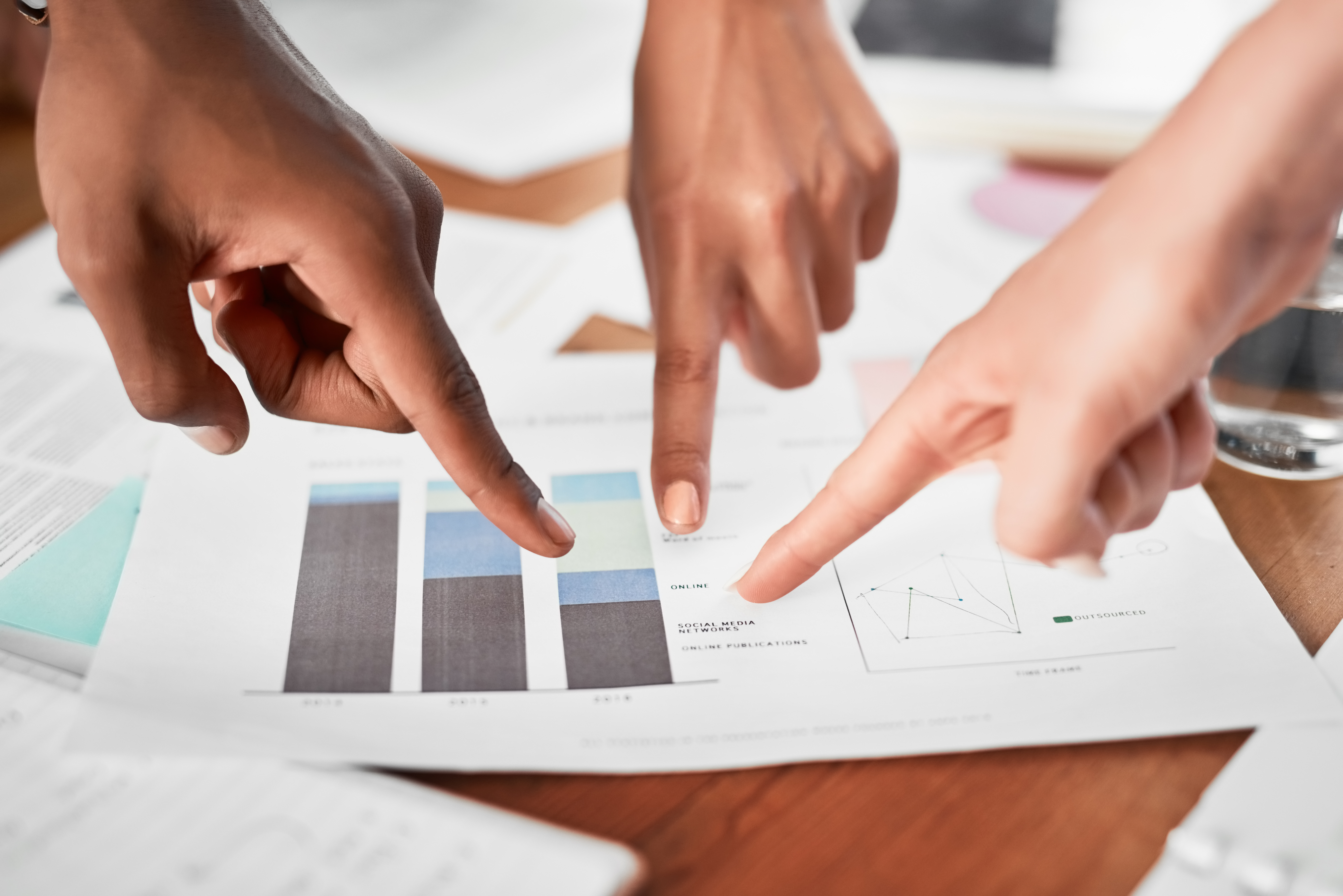 Closeup shot of a group of unrecognizable businesspeople pointing to paperwork in an office.